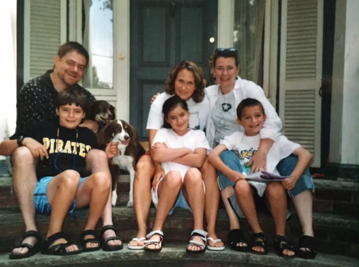 Jared and his family with their dogs on the porch steps
